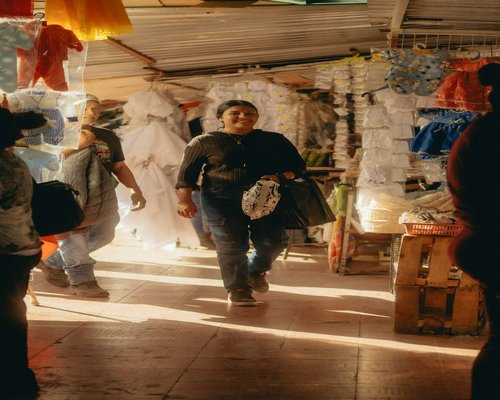 A person walking through a local market carrying a light bag